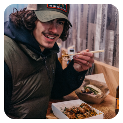 photo d'un homme qui mange avec des baguettes chinoise dans un restaurant
