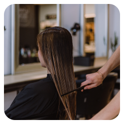 Photo d'une cliente qui se fait peigner les cheveux dans un salon de coiffure