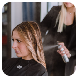 Photo d'une cliente qui se fait appliquer un produit sur ses cheveux dans un salon de coiffure