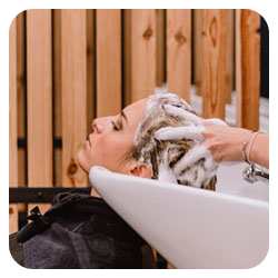 Photo d'une cliente qui se fait faire un shampoing par une coiffeuse dans un salon de coiffure